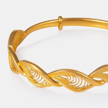 Close-up of filigree eyelet detailing on 24K gold adjustable bangle. 足金镂空凤凰眼雕花手镯细节特写