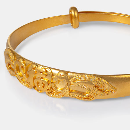 Close-up of phoenix motif and 福 character on 24K gold bangle

足金福字与凤凰图案手镯细节特写